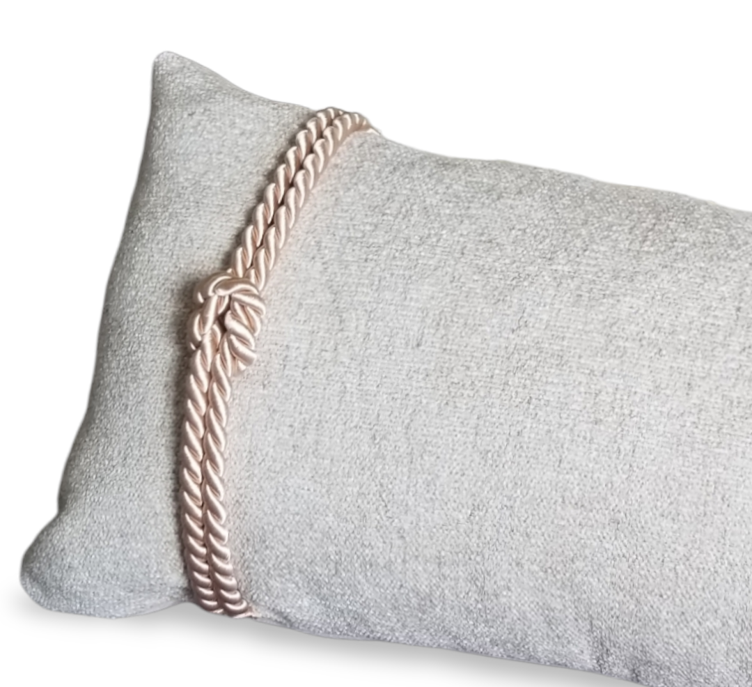 This beautiful designer throw pillow is perfect for adding a touch of nautical style to any room. The beige textured fabric features a rope knot detail, making it the perfect lumbar pillow cover for a beach-inspired look. The neutral color will coordinate with any existing décor, adding a touch of coastal charm.